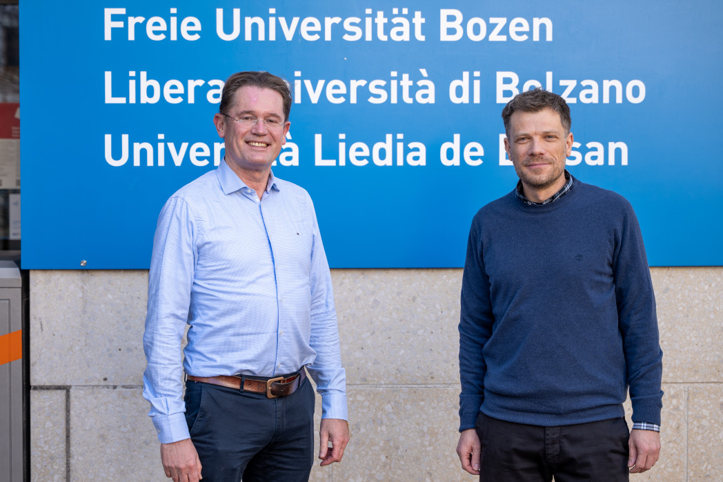 men who pose for a picture in front of unibz sign