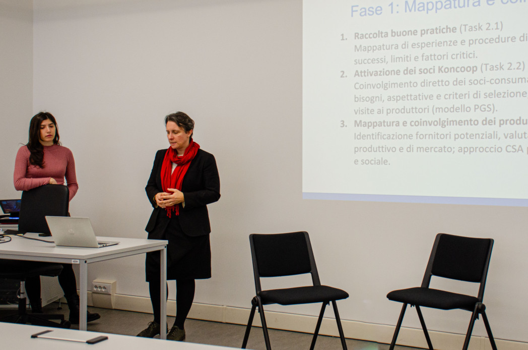 Eine Frau steht vor der Leinwand und erklärt.