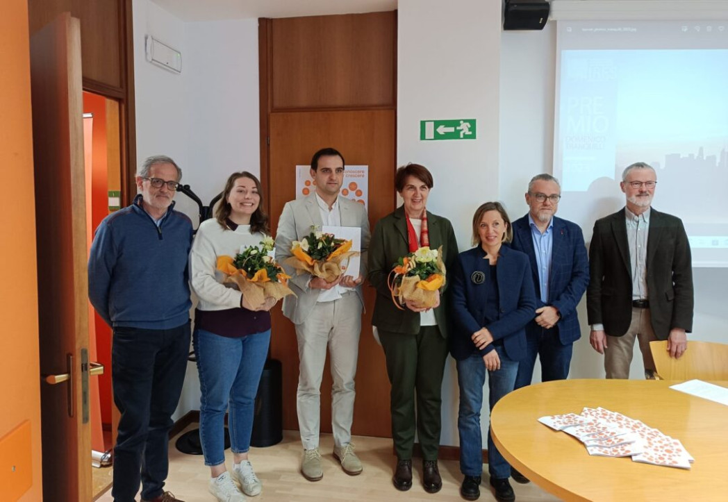 Sette persone sono in piedi in un'aula. Tre di loro hanno in mano un mazzo di fiori.