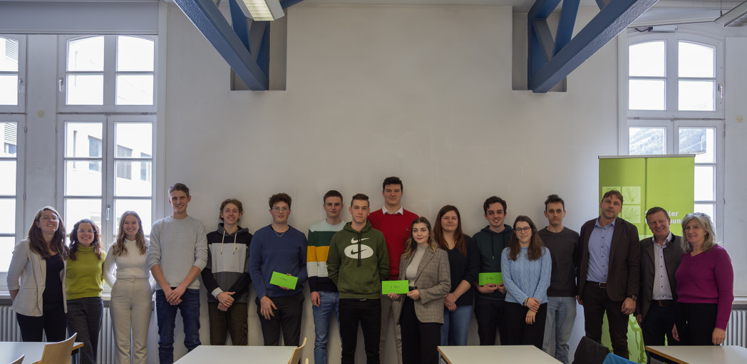 Siebzehn Personen stehen in einem Raum.