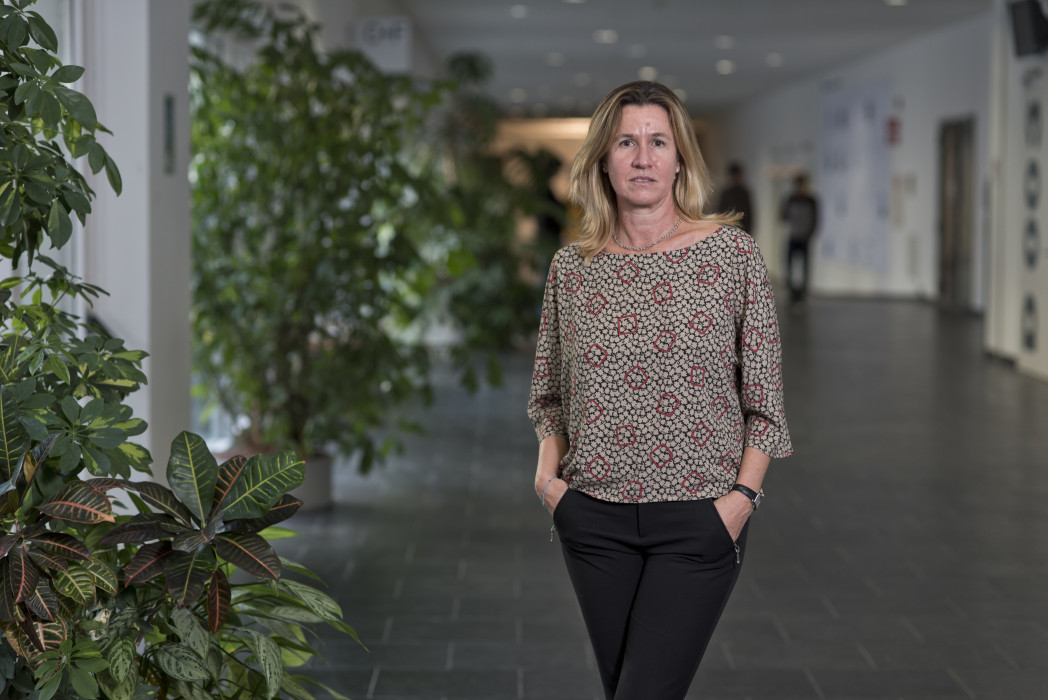 Donna in piedi con le mani nelle tasche in un corridoio che sorride