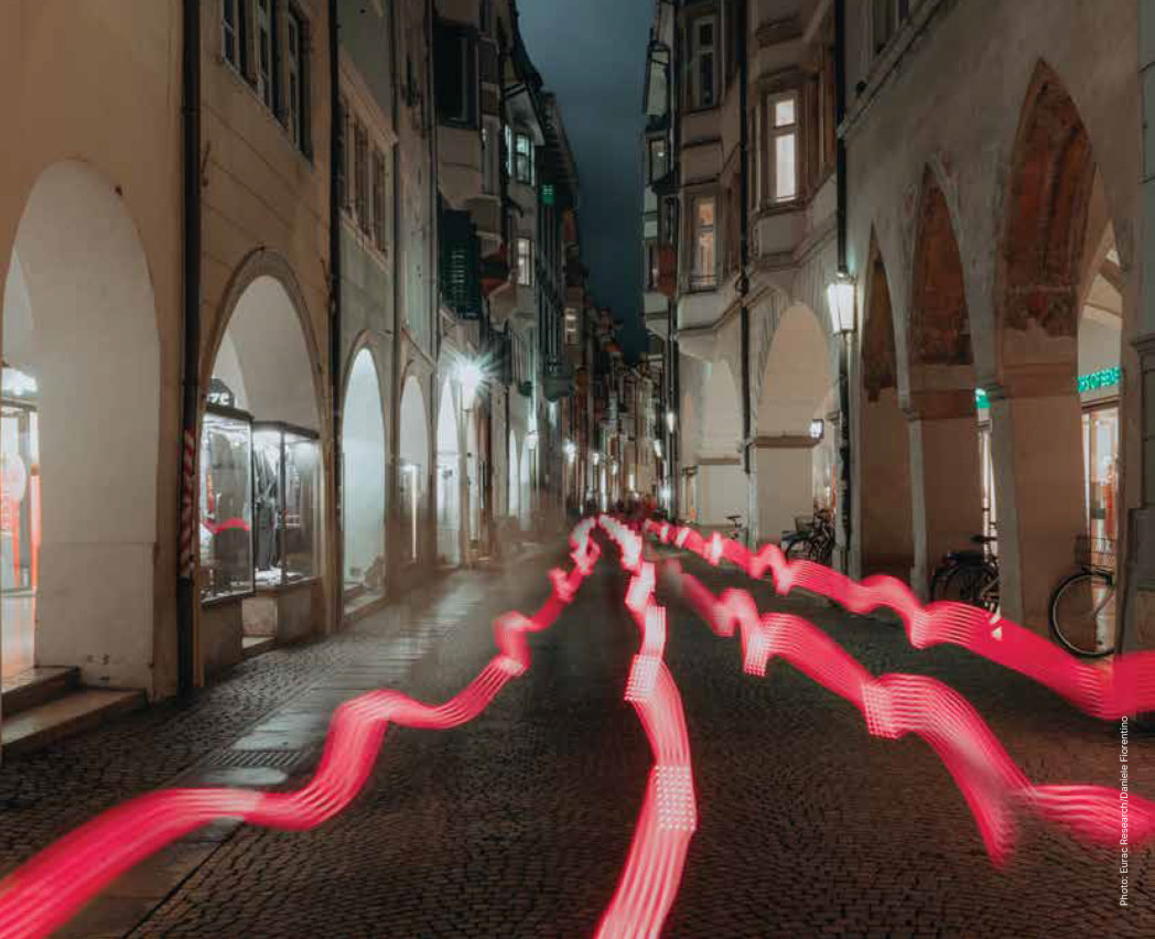 Cobblestone street with a series of red, wavy light trails moving through the center of the street