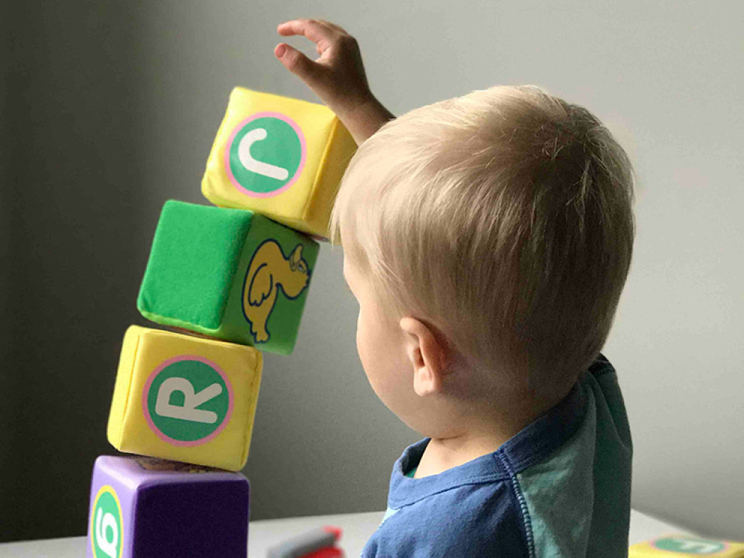 Un bambino impila blocchi giocattolo a forma di cubo uno sopra l'altro