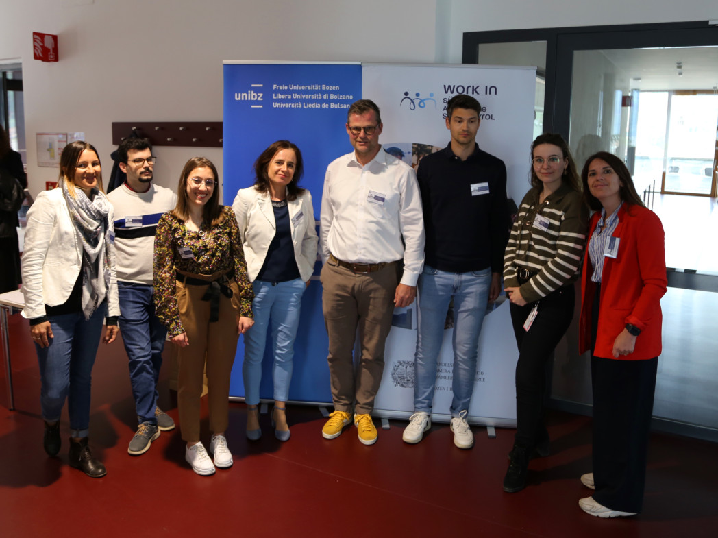 Otto persone sono in piedi davanti ad un banner dell'università.