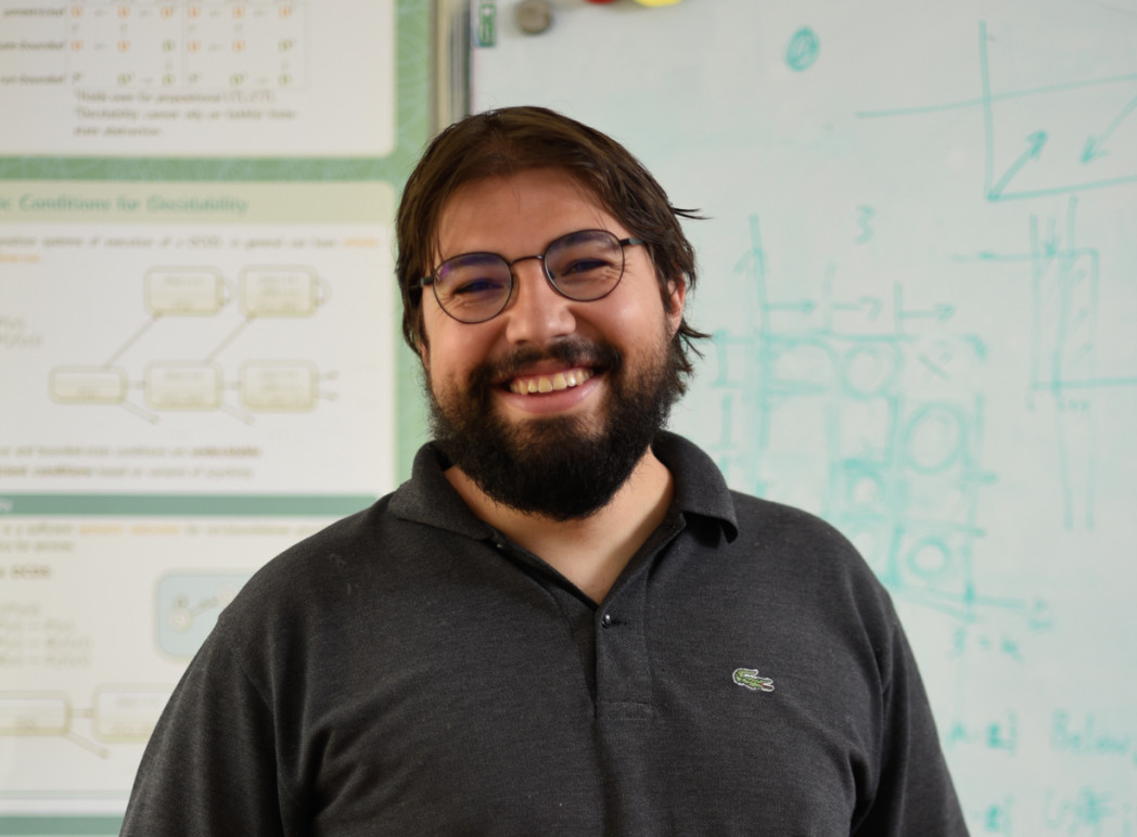 Ritratto di uomo sorridente con barba e occhiali in maglietta scura