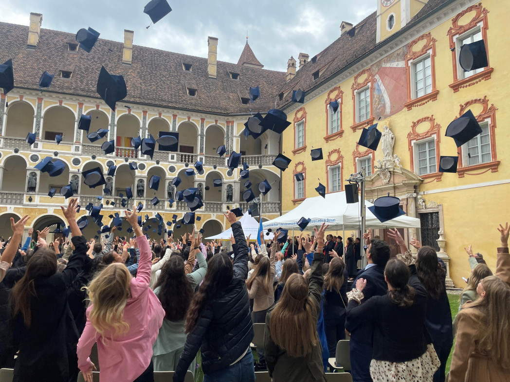 Die Absolventinnen und Absolventen werfen ihre Dimplomhüte im Innenhof der Hofburg Brixen