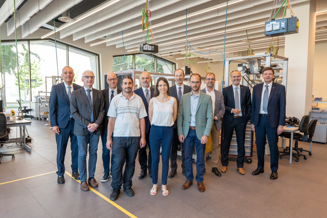 Gruppenportrait: 11 Personen stehen in einem modernen offenen Büro.