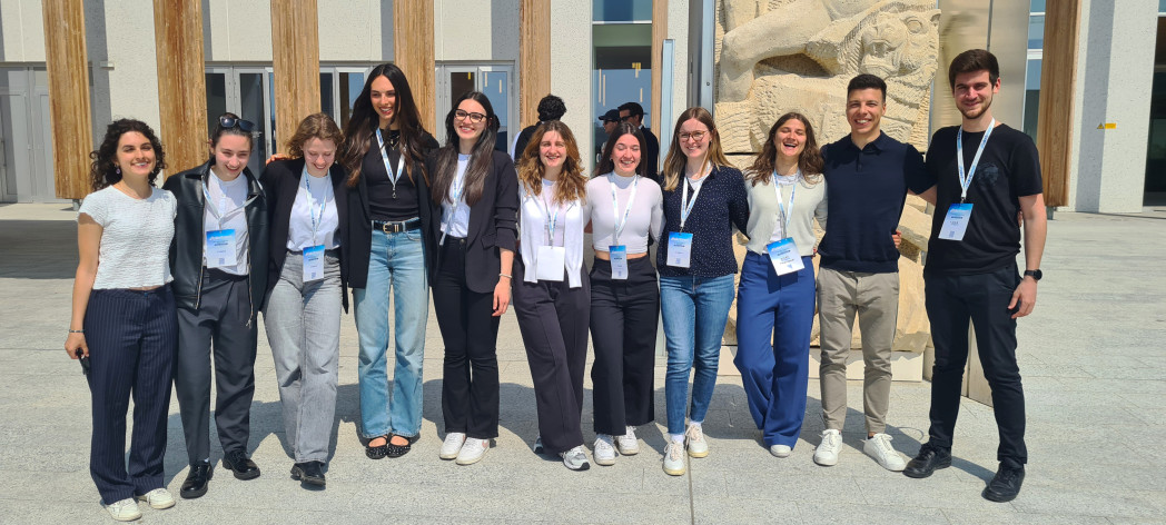 Un gruppo di giovani davanti a un edificio moderno, in posa sorridente.