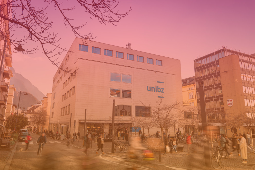 Building of unibz on a busy square, with blurred pedestrians creating a motion effect.