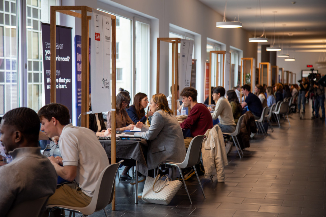 In un corridoio, le persone sono sedute ai tavoli e chiacchierano.