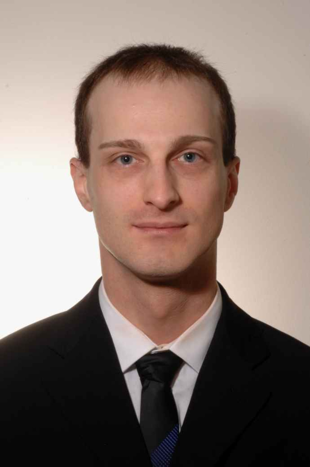 Ritratto a mezzobusto di un uomo vestito in giacca e cravatta nera.