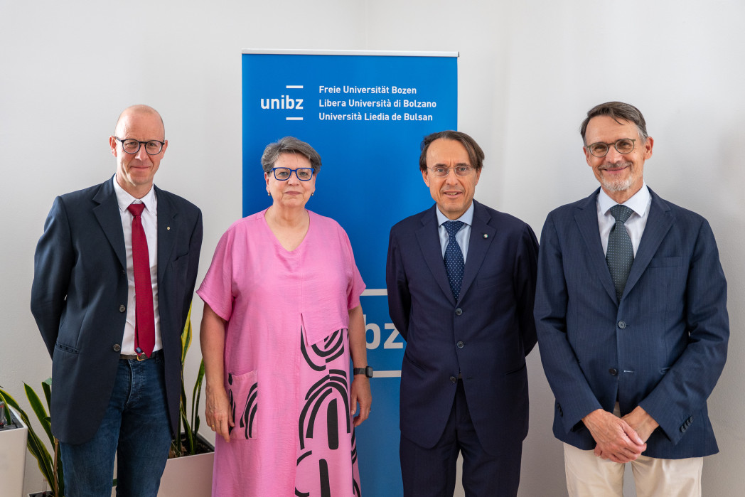 Ritratto di gruppo: Quattro persone davanti al roll up unibz