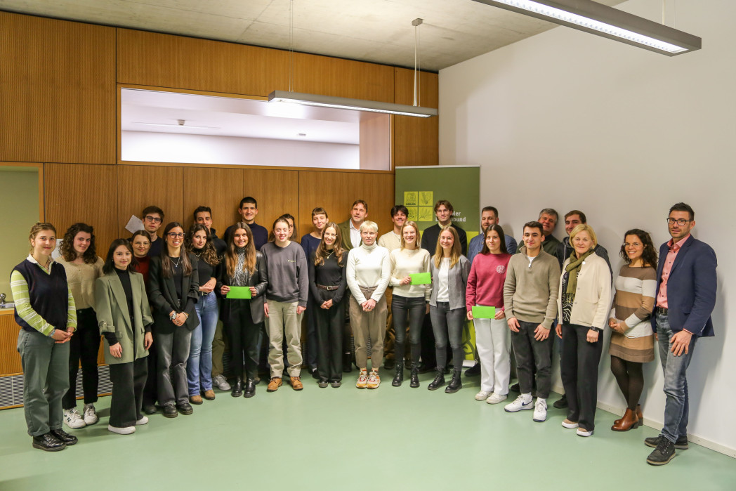 Un gruppo di persone è posizionato in semicerchio. Alcune persone tengono in mano un premio.