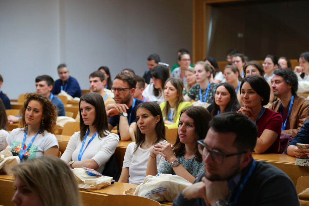 Viele Absolventinnen sitzen in einem Hörsaal.