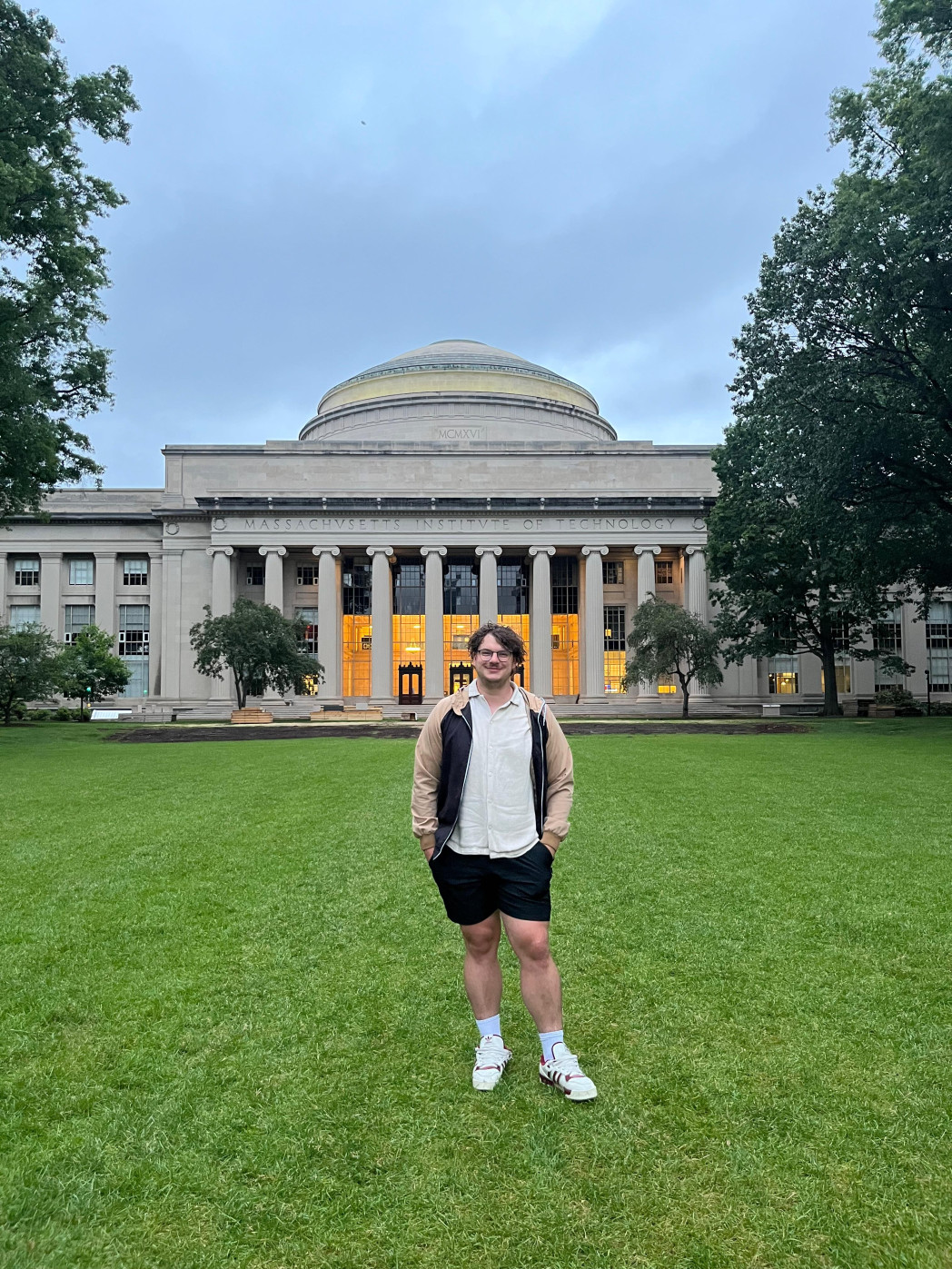 Junger Mann auf Wiese vor historischem Gebäude