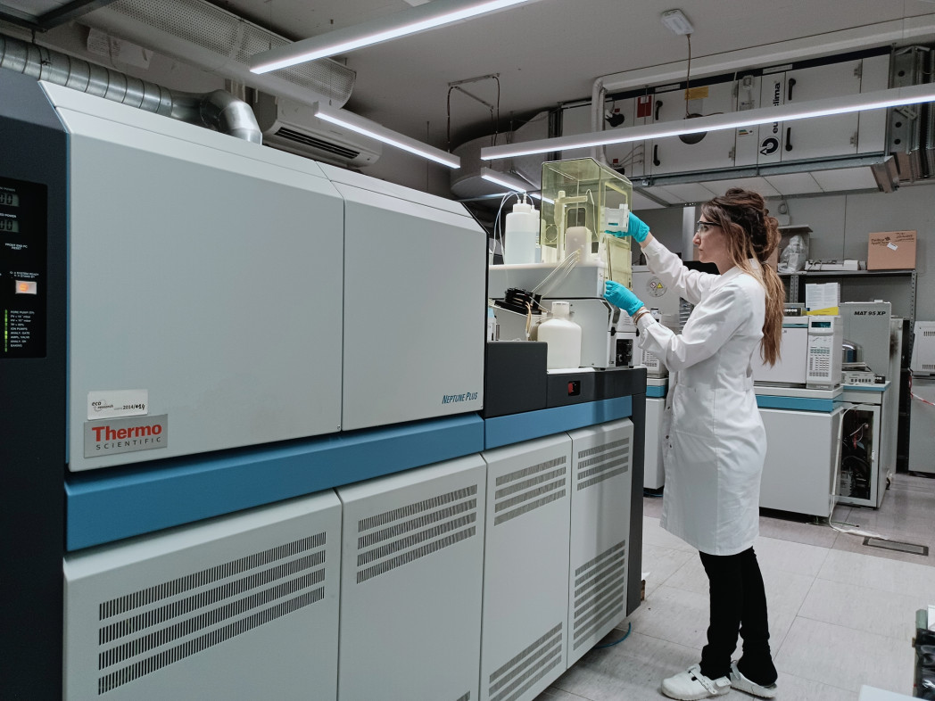 Scienziata in camice bianco da laboratorio che opera su grande macchina di analisi di laboratorio in moderna struttura di ricerca.