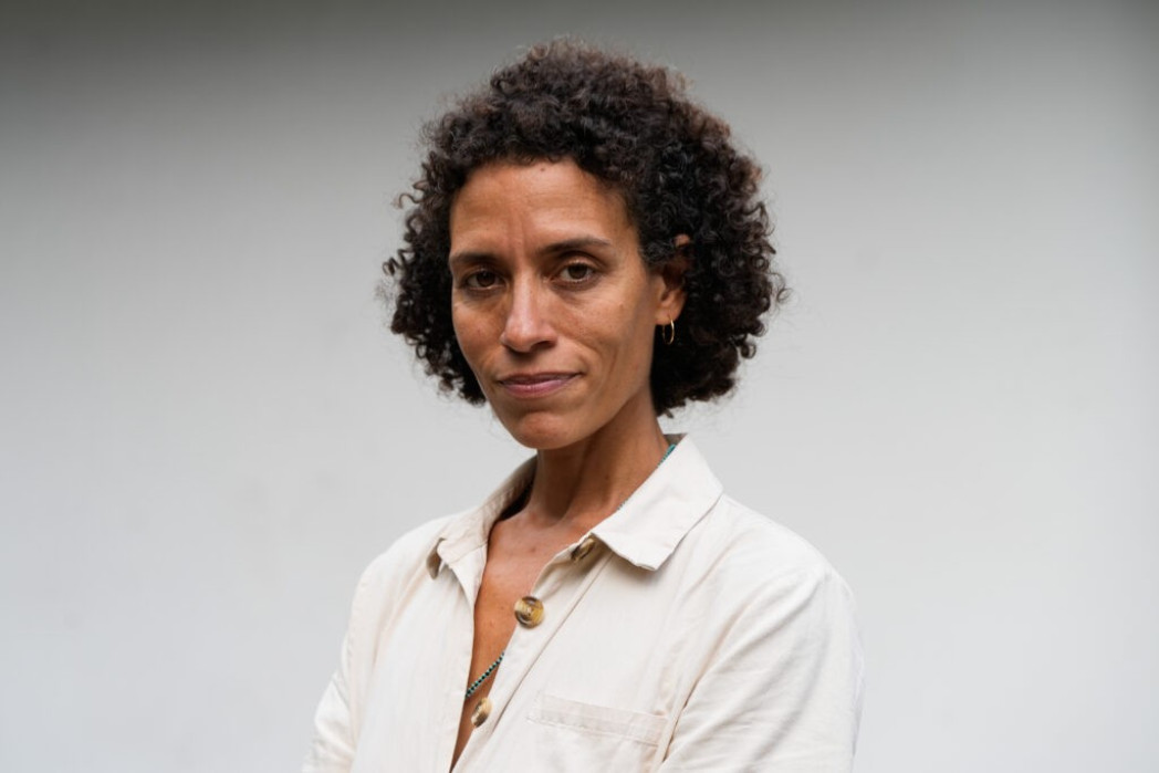 Ritratto professionale di donna con capelli ricci in camicia bianca su sfondo grigio