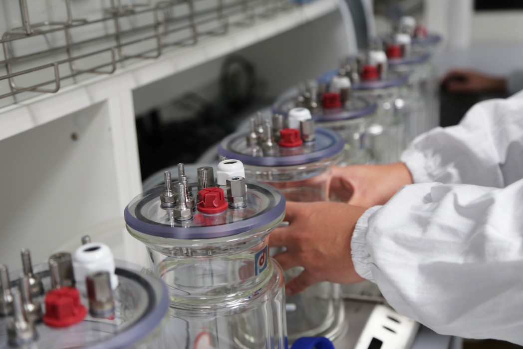 Hände greifen nach Behältern in einem Labor.