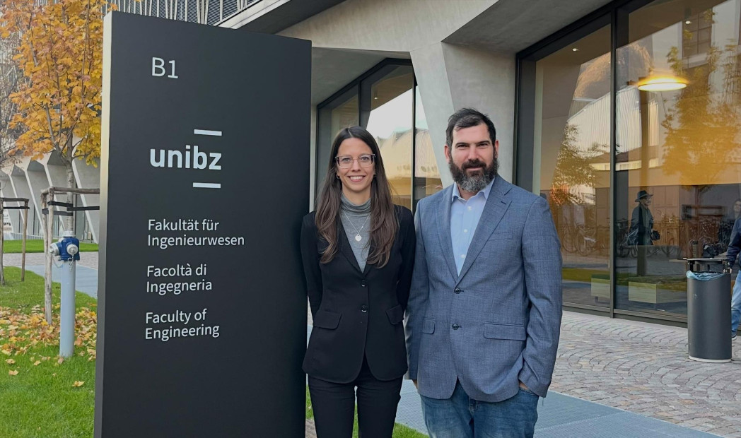 Due persone in posa davanti all’ingresso della Facoltà di Ingegneria della unibz.