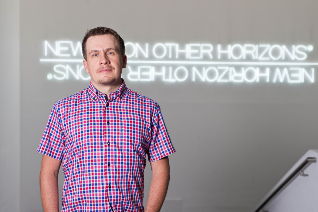 Il professore Davide Ferrari in un corridoio davanti a un'insegna al neon.