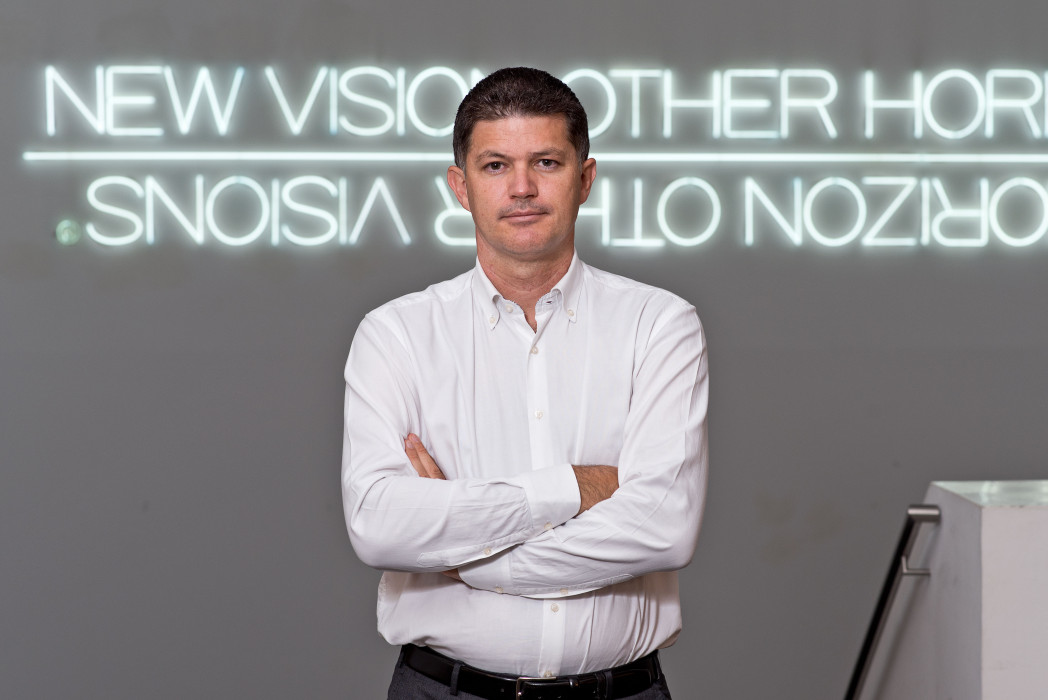Una persona si trova a braccia conserte in una tromba delle scale davanti a un'insegna al neon.