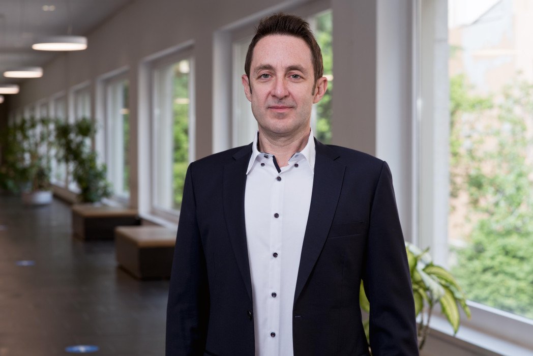 Porträtbild von Prof. Sascha Kraus in einem Korridor mit Fenstern im Hintergrund.