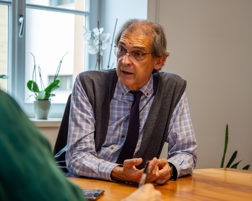 Rector Lugli is sitting at a table in front of a window