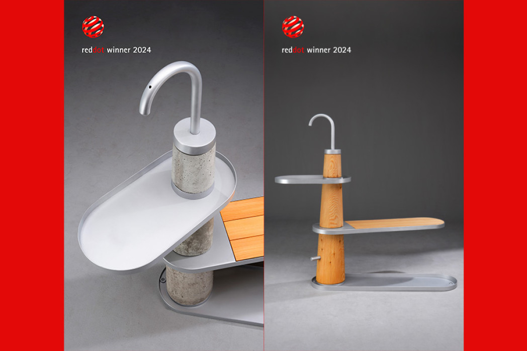 Der Brunnen des Gewinnerteams ist zu sehen. Er besteht aus einer Holzsäule, aus der links und rechts zwei Flächen ragen. 