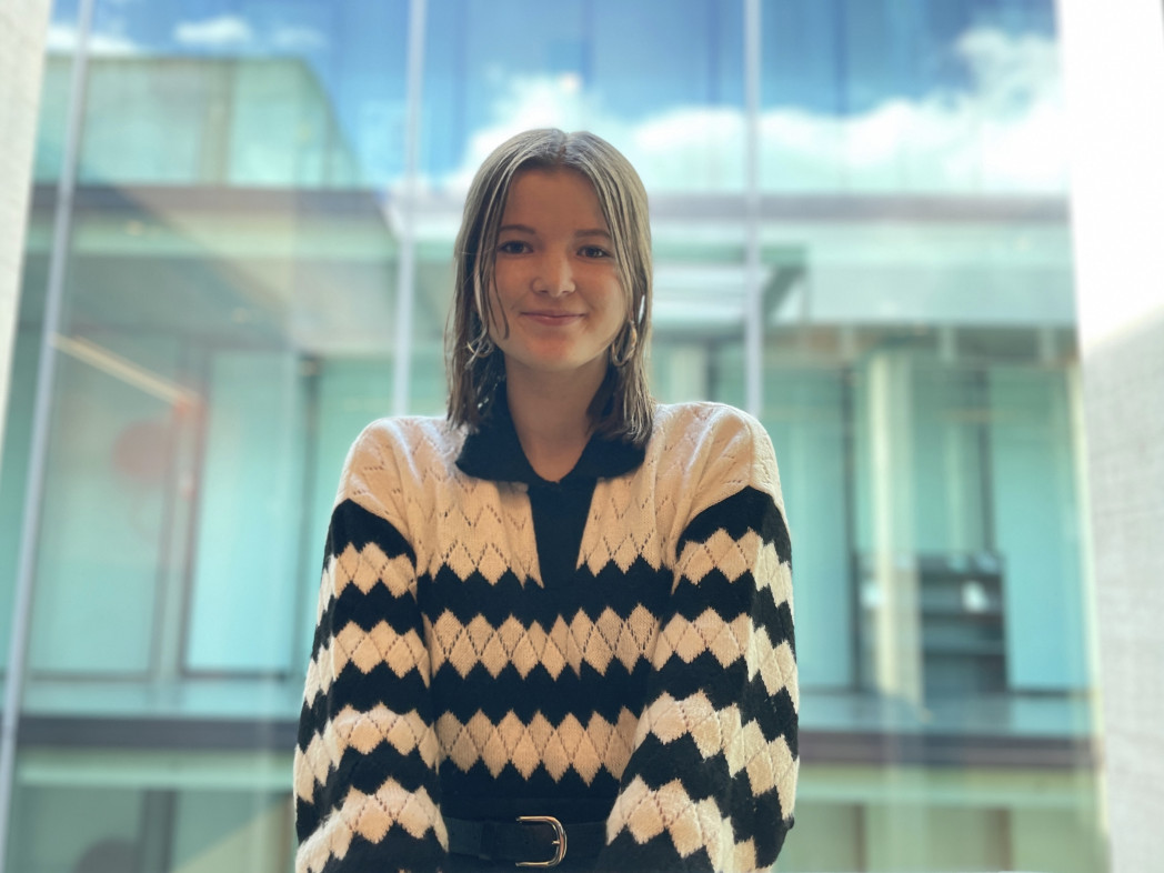 Junge Frau steht vor einer Glasfront.