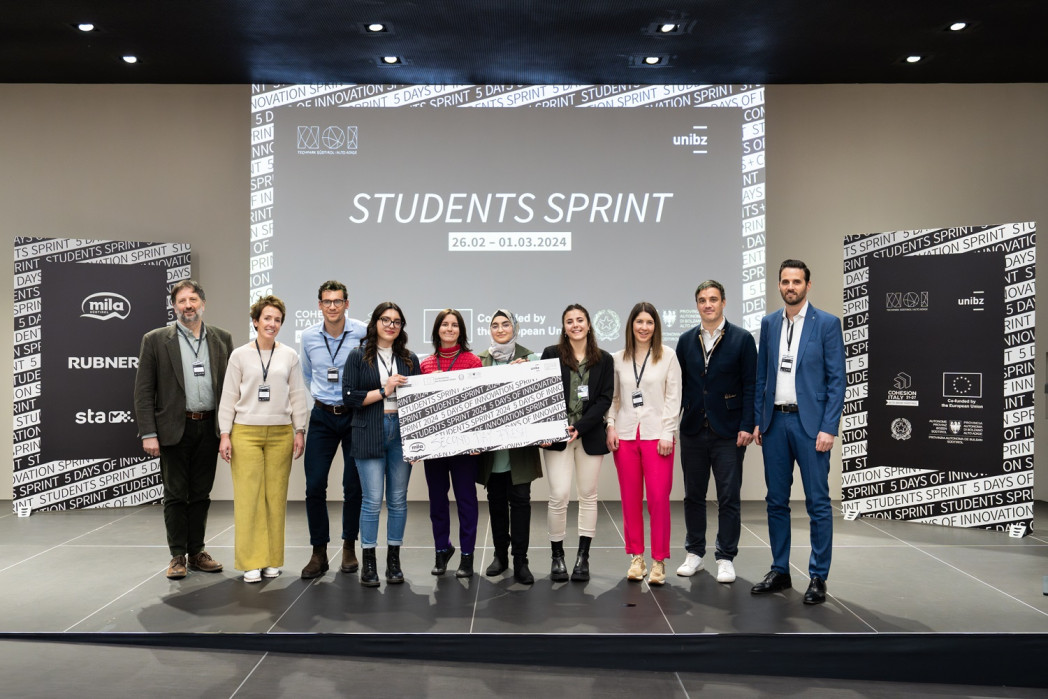 Personen stehen auf einer Bühne. Einige halten ein Schild in der Hand.