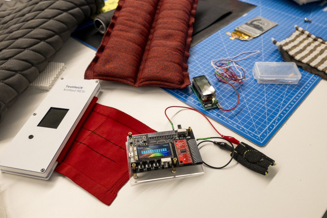 Verschiedende Textilien, Kabel und Sensoren und eine Schneidematte liegen auf einem Tisch
