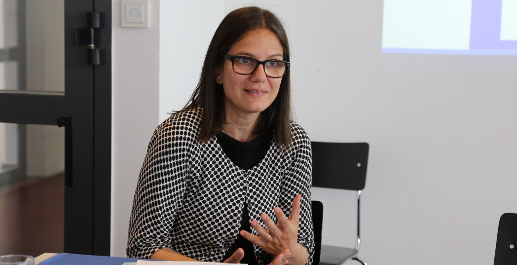 Frau sitzt an Tisch und gestikuliert