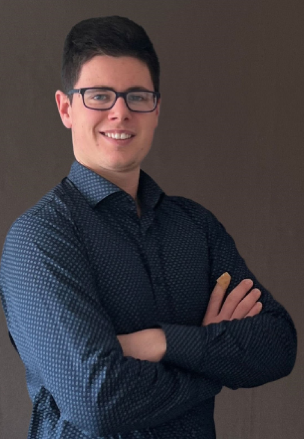 Mann mit Brille, blauem Hemd und verschränkten Armen. 