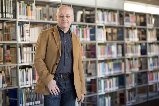 Prof. Günter Schamel in braunem Sakko vor Bücherwand