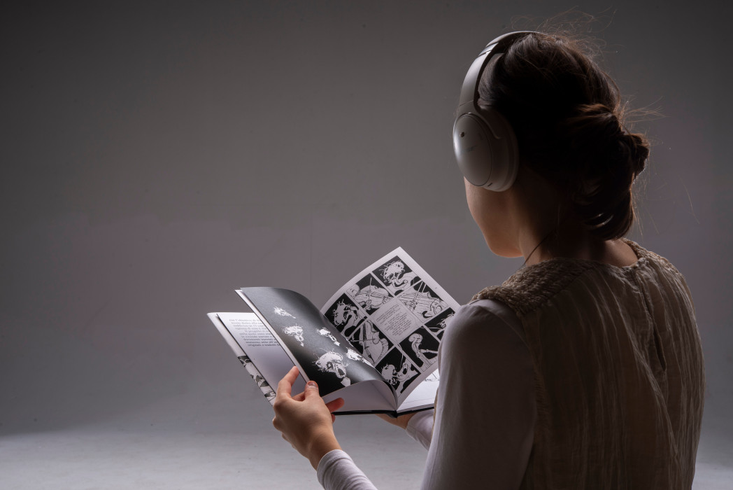Una donna con le cuffie tiene tra le mani una pubblicazione.