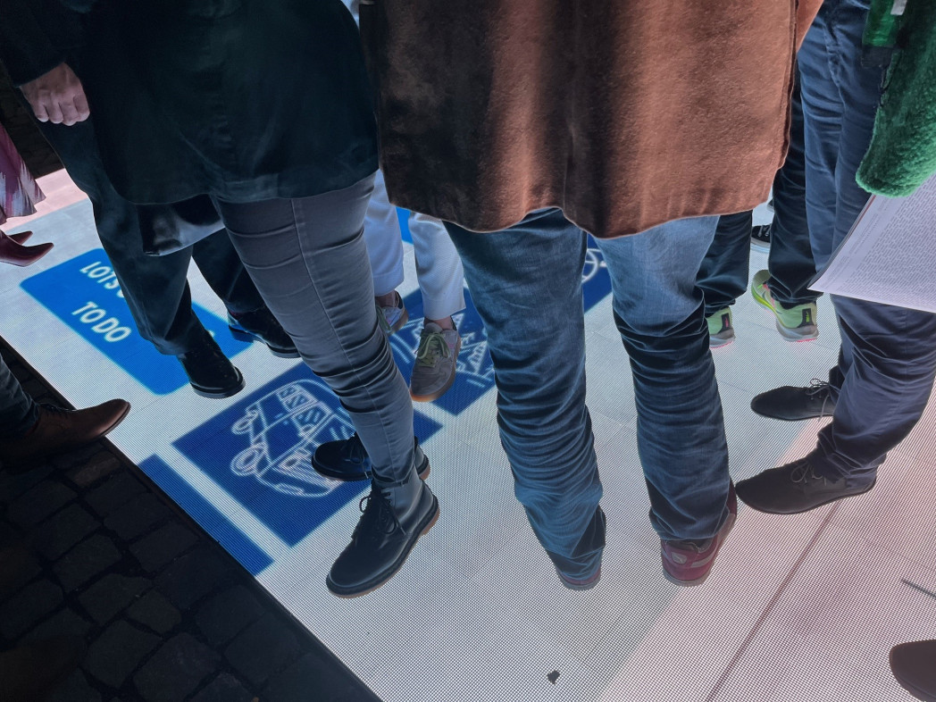 Ein begehbarer LED-Bildschirm auf dem Zeichen und Muster zu sehen sind und auf dem Menschen stehen.