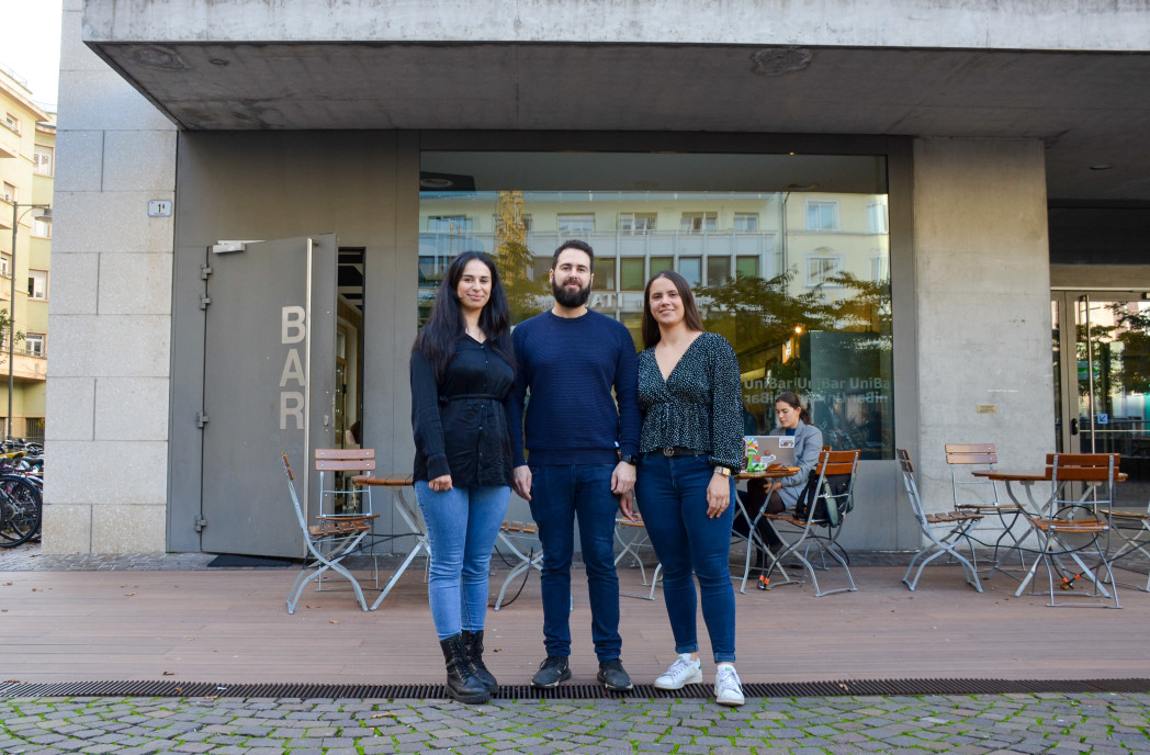Drei Personen stehen vor einer Bar.