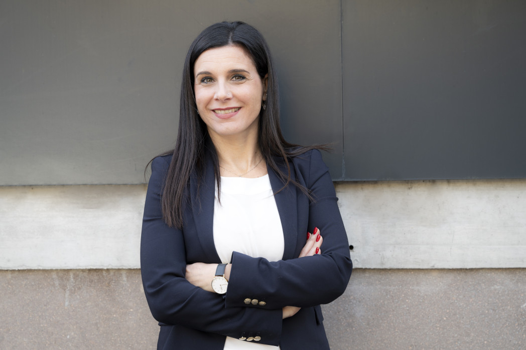 Frau mit verschränkten Armen steht vor einer Wand.