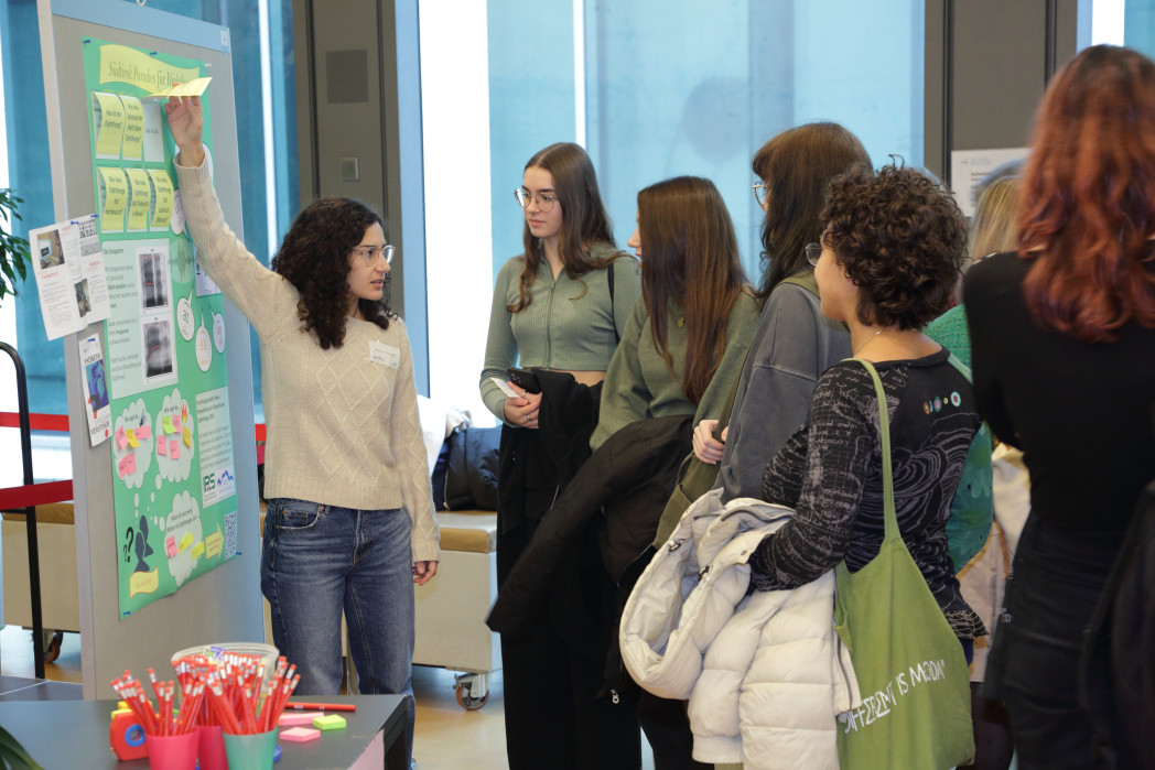Gruppe von Menschen schaut auf junge Frau, die anhand von Poster etwas erklärt