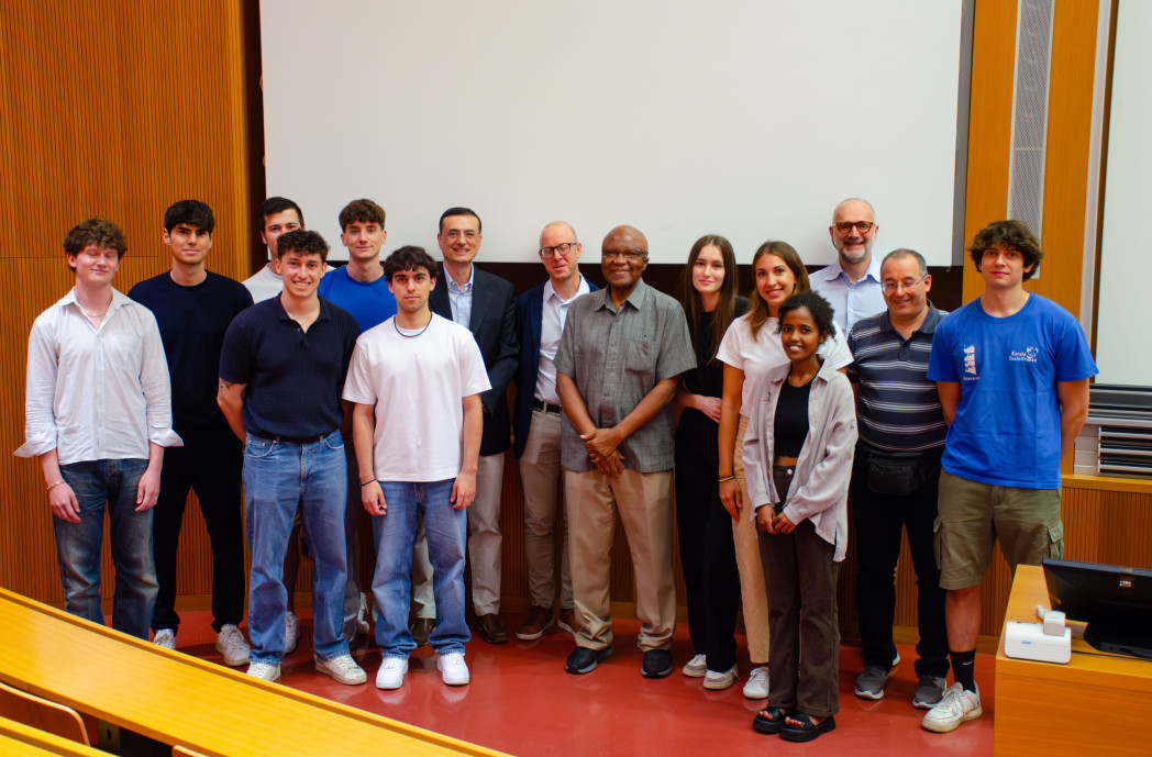 Group of people standing in front of a screen in a lecture theatre.