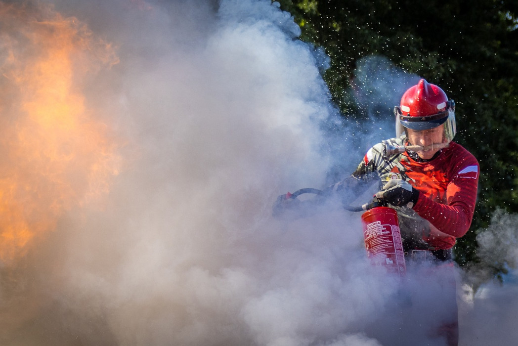 Feuer mit starker Rauchentwicklung. Ein Feuerwehrmann löscht das Feuer mit einem Feuerlöscher.