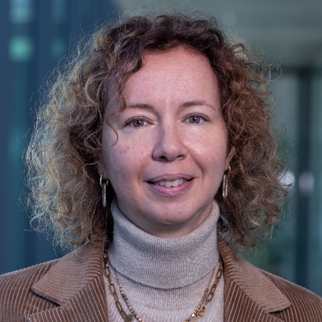 Ritratto di donna sorridente con capelli ricci che indossa dolcevita beige e collana.